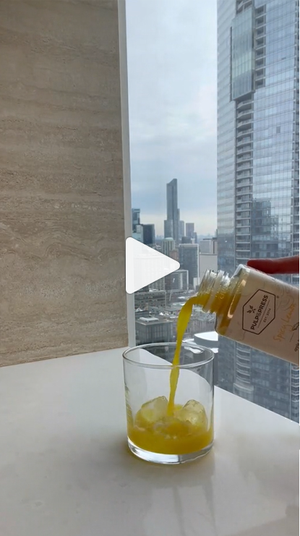 video of person making a mocktail using pulp & press cold pressed juice in front of downtown building window